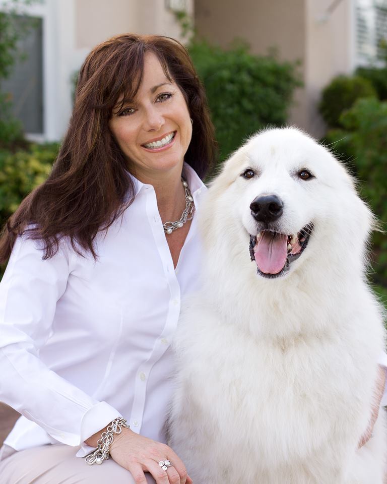 A woman standing next to a white dog.